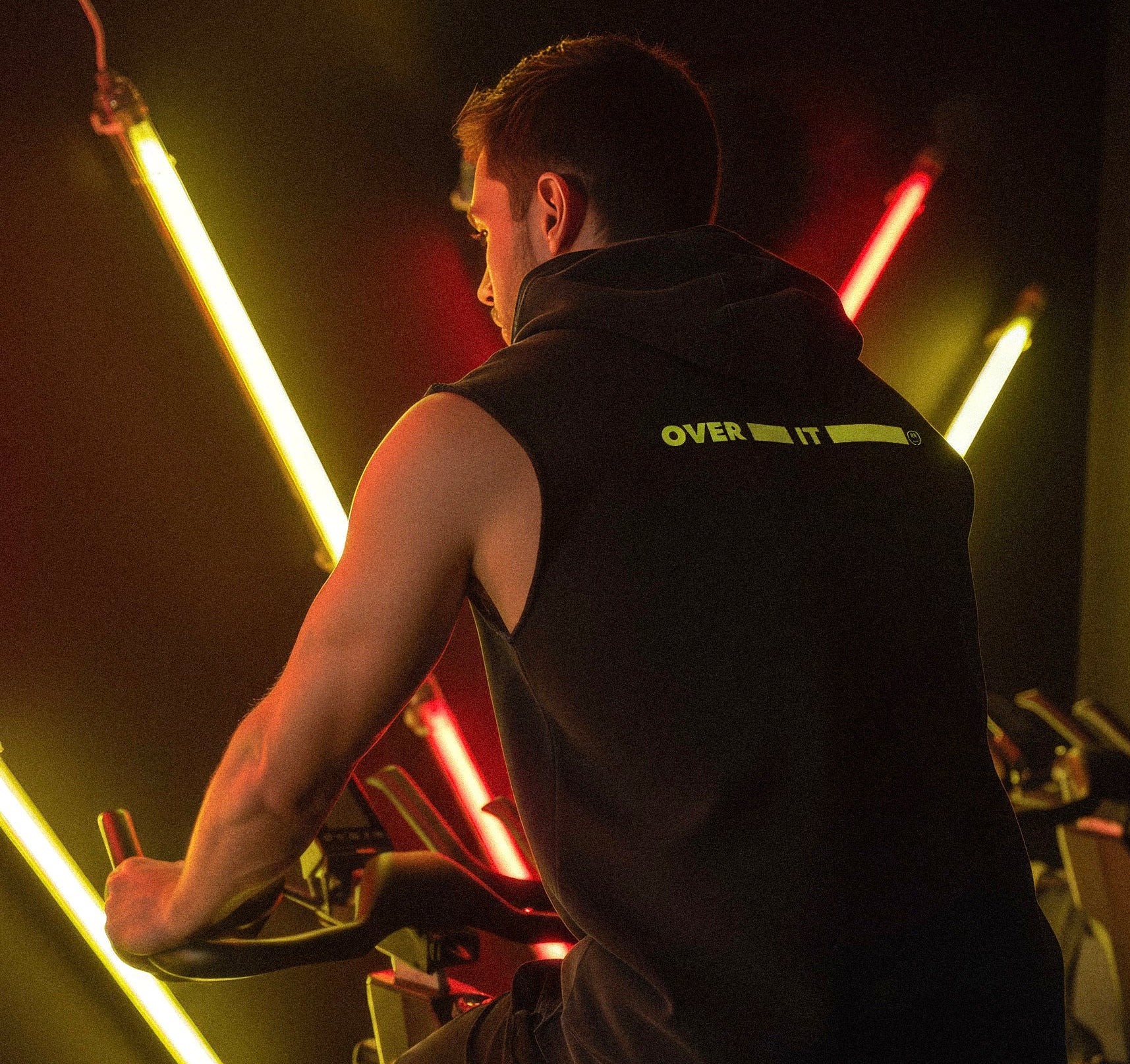 Person using a stationary bike in a dark room with neon lights