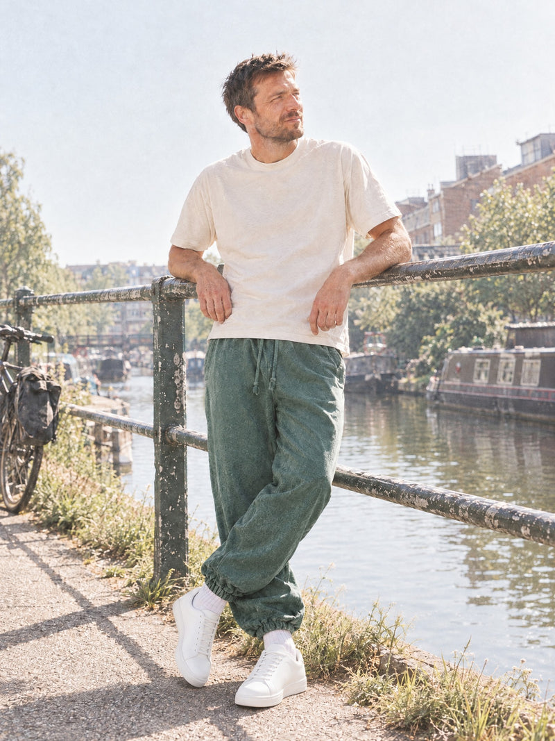Man wearing the Men's Snow Wash Heavyweight Joggers in Blackish Green with a cream t-shirt