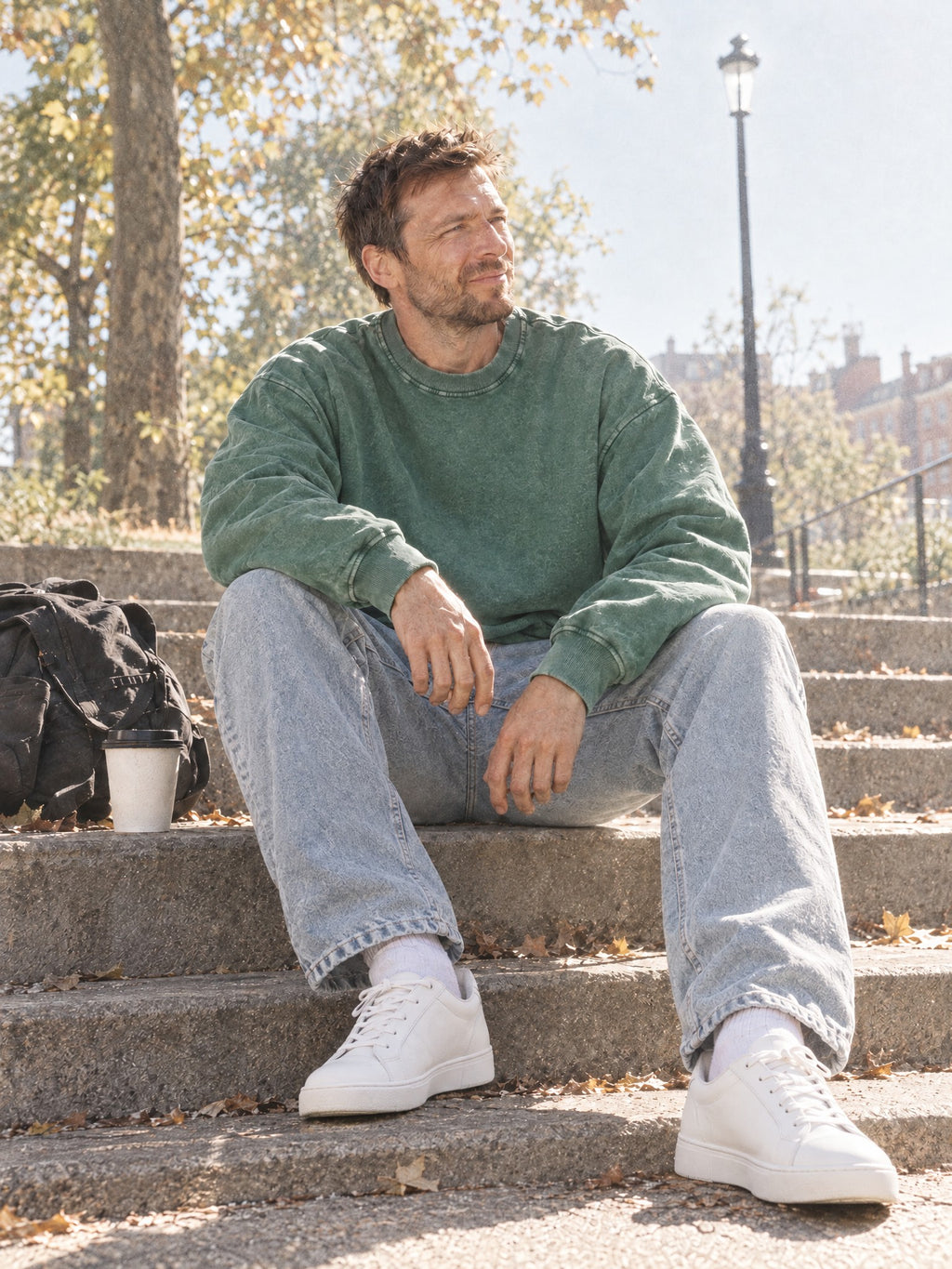 Man wearing the Men's Snow Wash Oversized Sweatshirt in Blackish Green with light-wash jeans
