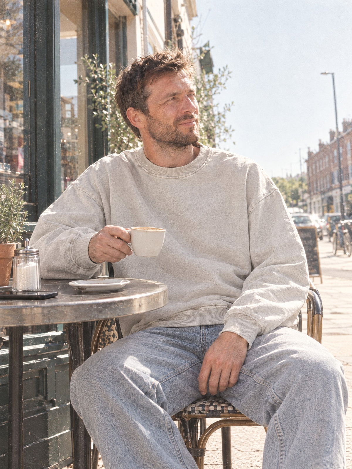 Man wearing the Men's Snow Wash Oversized Sweatshirt in Light Apricot at a cafe table